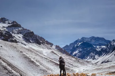 Laden Sie Ihre Batterien Während Einer Reise Nach Argentinien Auf : Zwei Leute, die zu Fuß des schneebedeckten Aconcagua-Berges umarmen